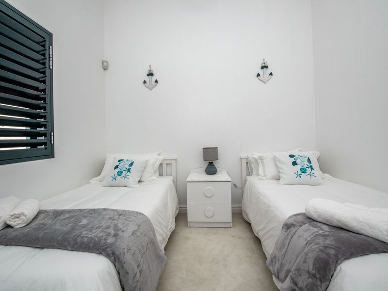 A well-maintained bedroom featuring neutral walls, carpeted flooring, and a shuttered window, providing a clean and functional sleeping space.