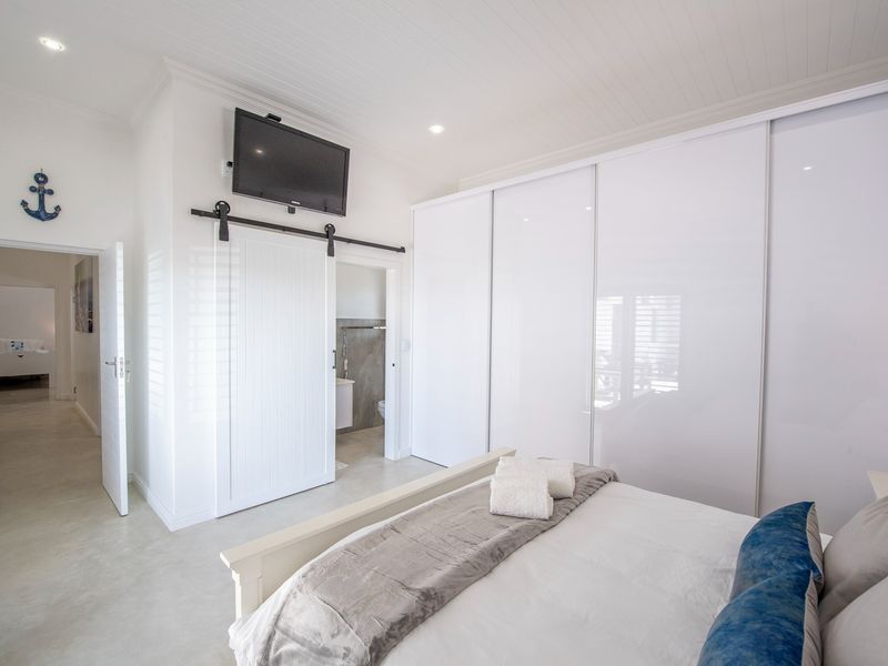 Modern bedroom featuring a large built-in sliding door wardrobe, tongue and groove ceiling, and a barn-style sliding door leading to an en-suite bathroom.