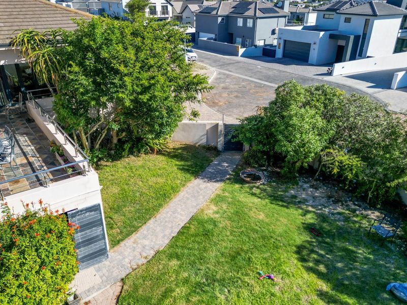 Aerial view of the property showing a tiled patio with stainless steel balustrades, a paved garden walkway, and surrounding residential neighborhood.