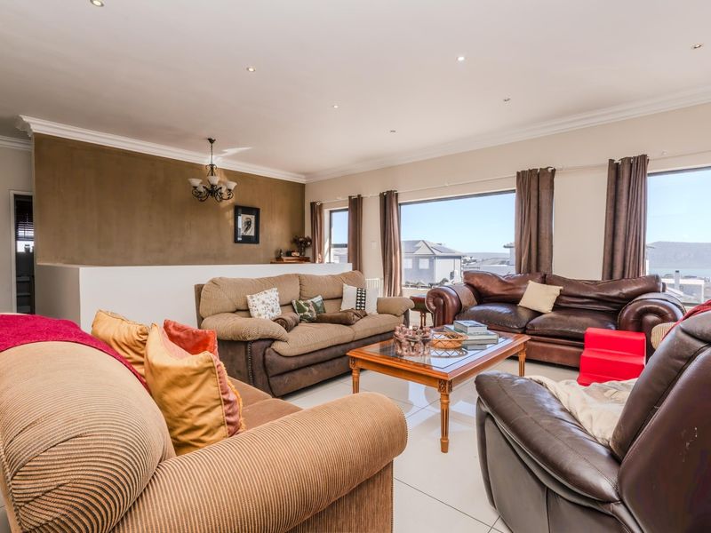 Spacious living room featuring large windows with natural light, tiled flooring, recessed downlights, and a neutral color palette with a feature wall.
