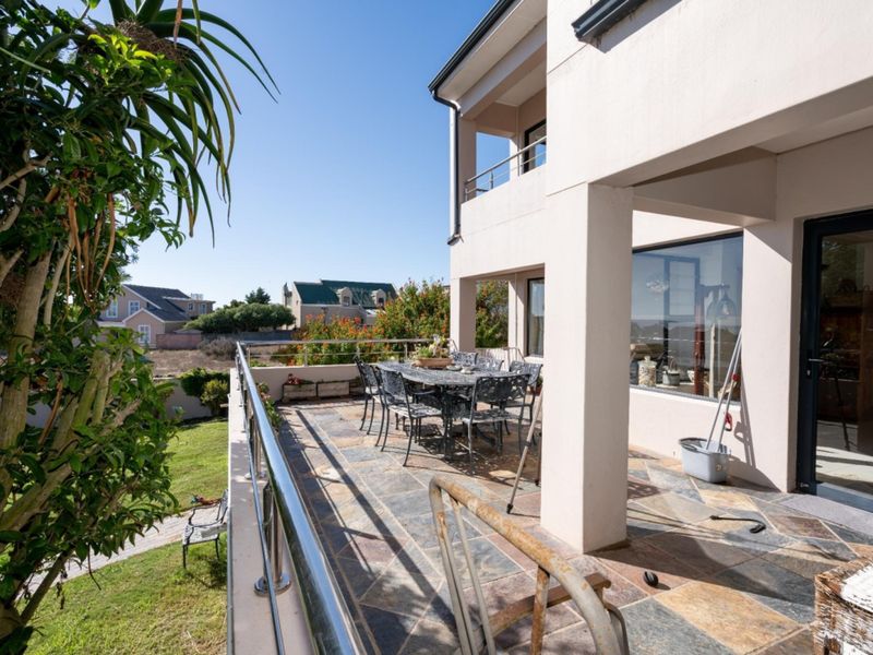 Spacious covered balcony featuring stone tile flooring and a stainless steel balustrade, offering an ideal outdoor space for relaxation and entertaining.