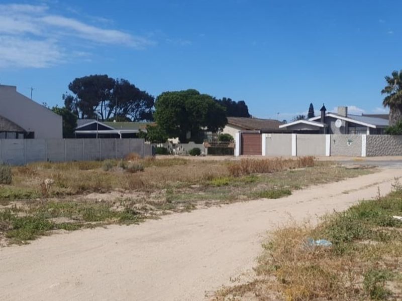 A vacant residential plot featuring an unpaved access road and perimeter walling, situated in an established neighbourhood.