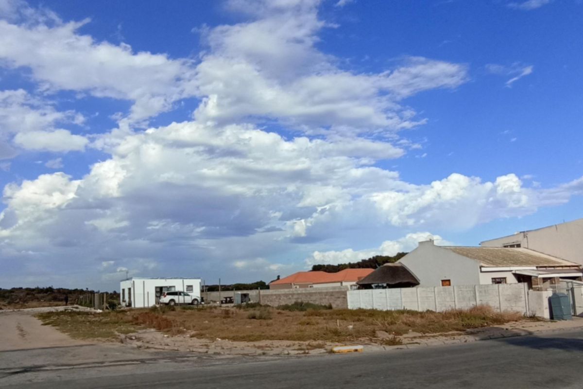 A vacant residential plot featuring a precast concrete boundary wall, situated in a developing neighborhood with access to a local road.