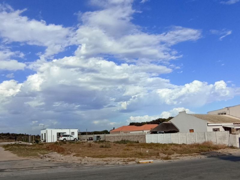 A vacant residential plot featuring a precast concrete boundary wall, situated in a developing neighborhood with access to a local road.