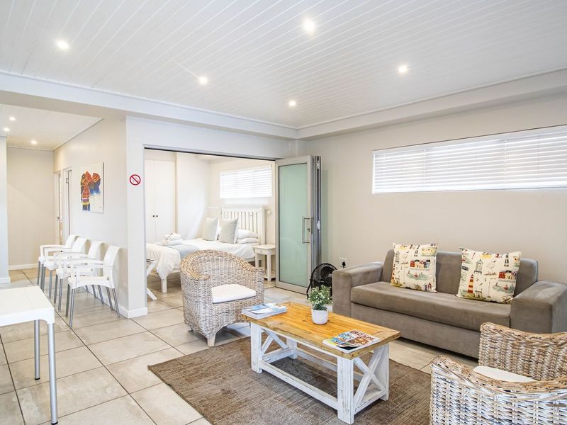 Open-plan living area featuring tiled floors, recessed lighting, and a tongue and groove ceiling, with an adjoining bedroom accessible via a glass panel door.