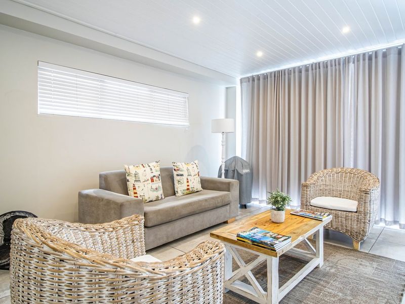 A bright and well-maintained living area featuring tiled flooring, recessed downlighting, and a tongue and groove ceiling with floor-to-ceiling curtain treatments.