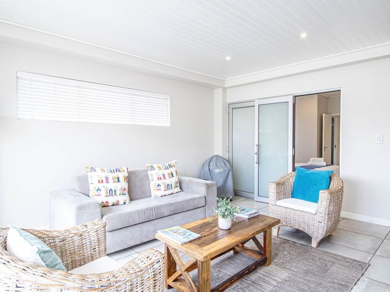 Bright and airy living room featuring tiled flooring, recessed downlighting, and sliding glass doors leading to an adjacent space.