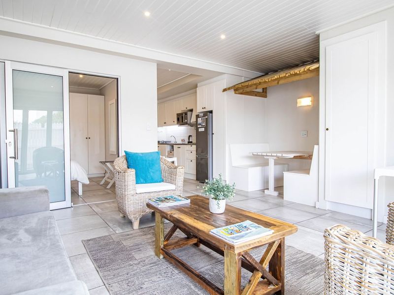 Bright open-plan living area featuring tiled floors, recessed lighting, and a built-in dining nook, seamlessly connecting to the kitchen and adjacent bedroom.