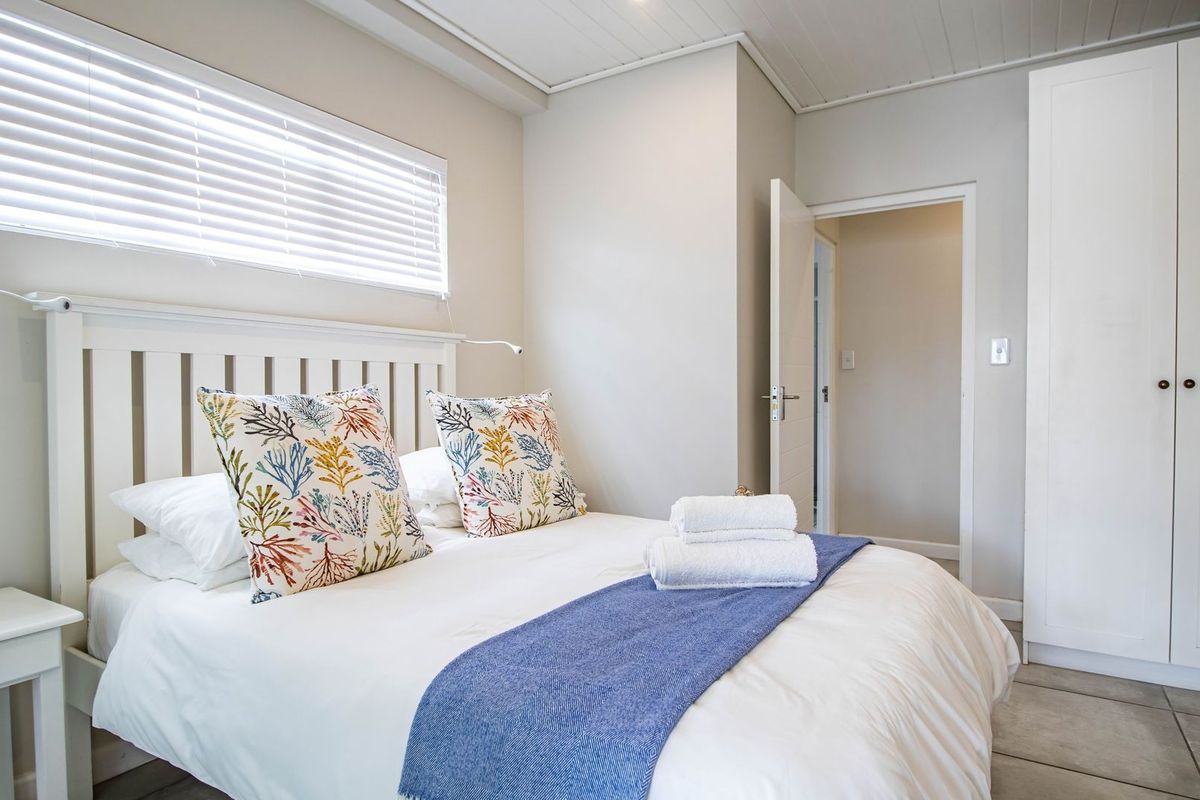 A bright and well-maintained bedroom featuring built-in cabinetry, tiled flooring, and venetian blinds, offering a clean and functional living space.