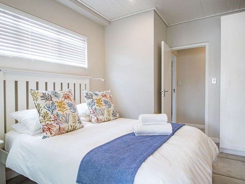 A bright and well-maintained bedroom featuring built-in cabinetry, tiled flooring, and venetian blinds, offering a clean and functional living space.