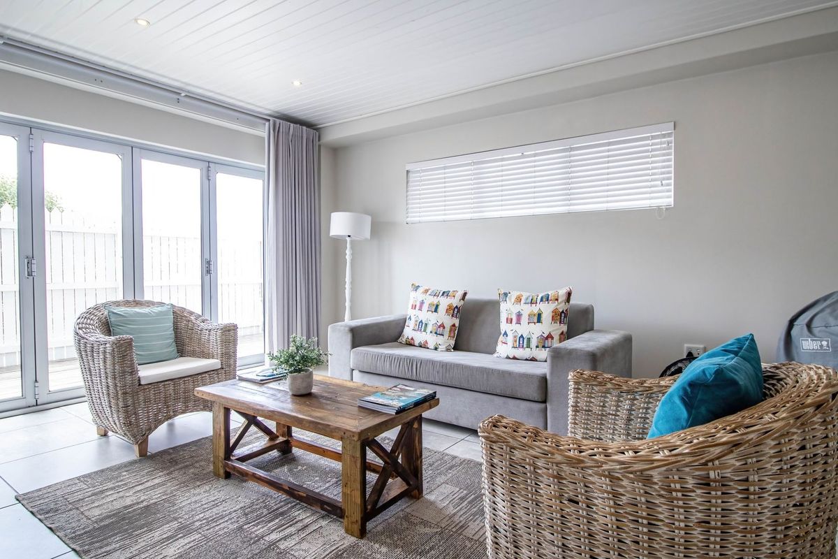 A bright living room featuring tiled flooring, recessed downlights, and large bi-fold doors providing seamless access to the outdoor area.