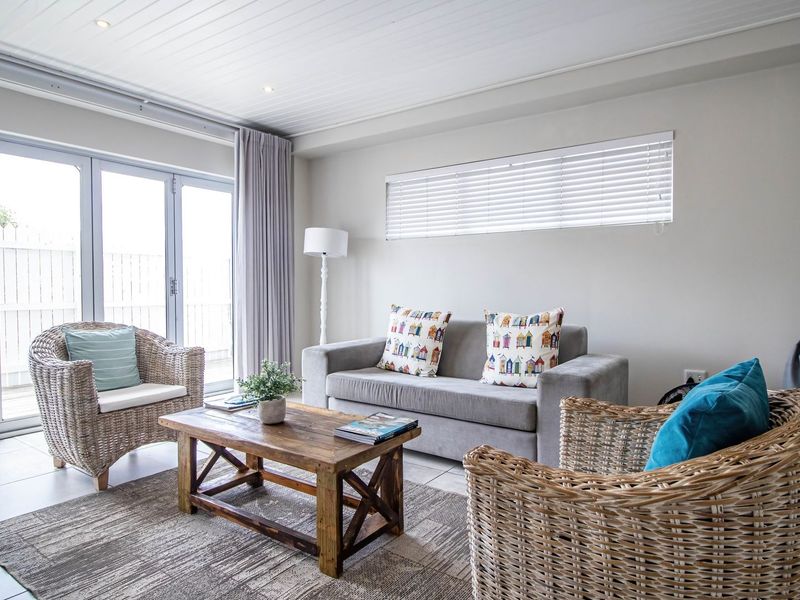 A bright living room featuring tiled flooring, recessed downlights, and large bi-fold doors providing seamless access to the outdoor area.
