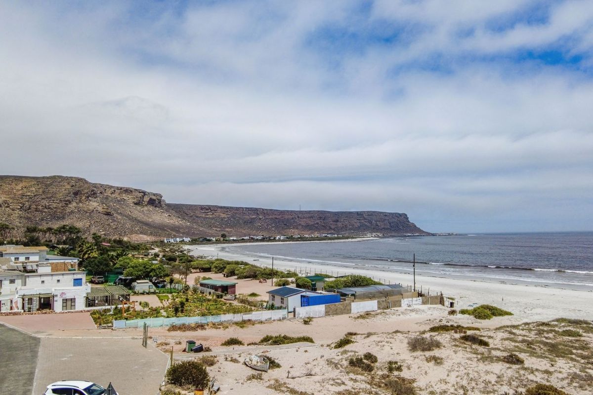 An aerial view of the coastal property, showcasing its proximity to the beach, surrounding landscape, and local neighborhood setting.