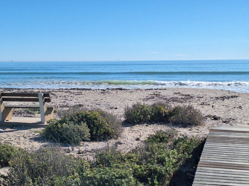 A scenic view of the coastline featuring a wooden boardwalk leading towards the beach and ocean.
