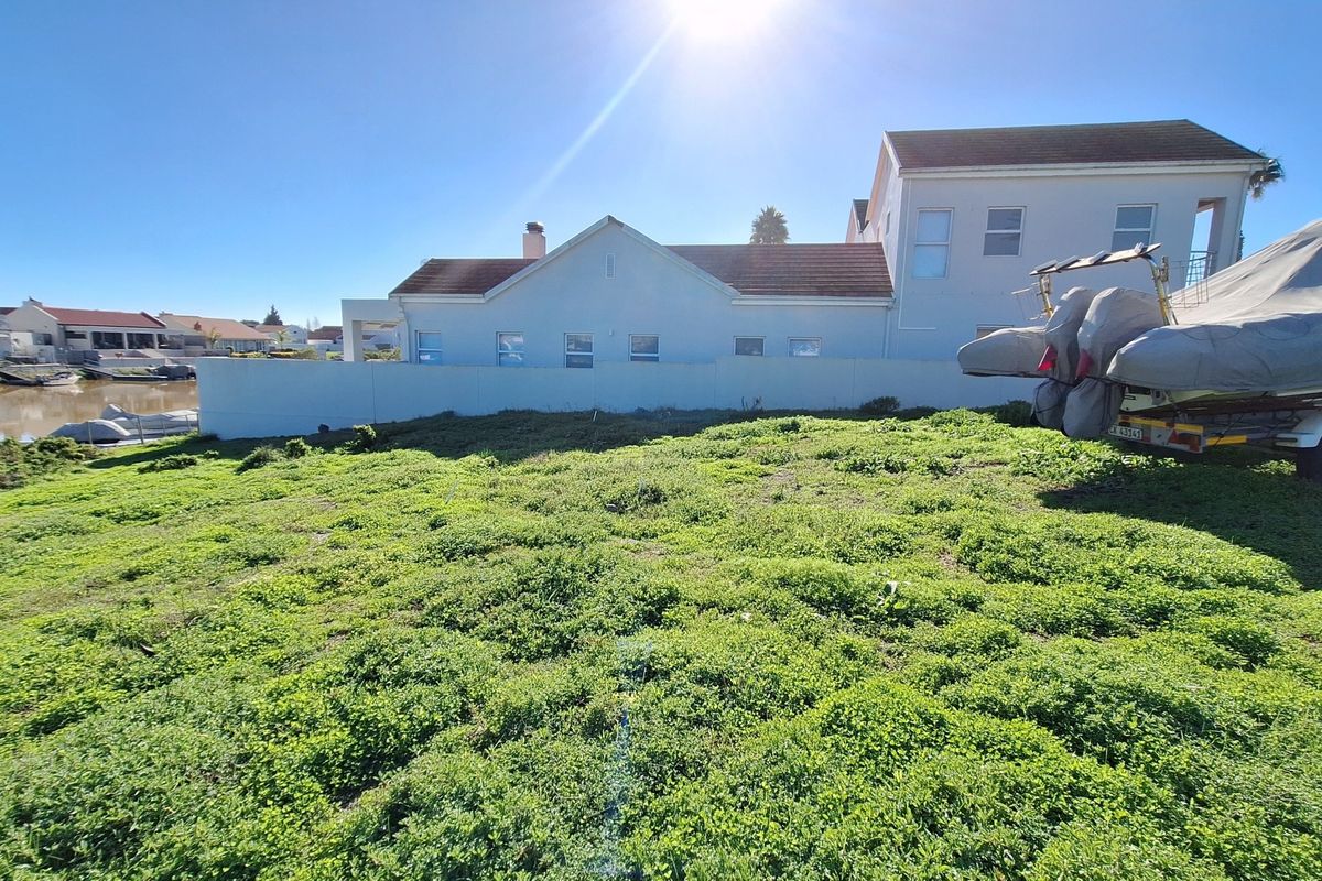 A vacant residential plot featuring a boundary wall and direct waterfront access, offering potential for development in a quiet canal-side setting.