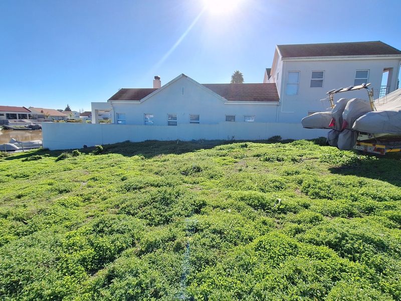 A vacant residential plot featuring a boundary wall and direct waterfront access, offering potential for development in a quiet canal-side setting.