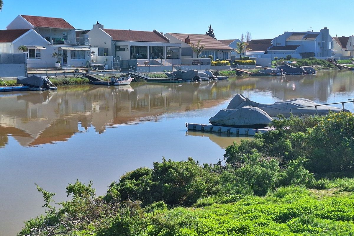A scenic view of a residential canal waterway featuring private jetties and well-maintained waterfront properties.