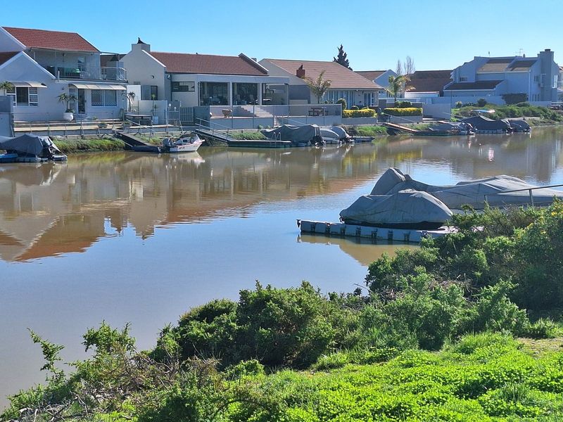 A scenic view of a residential canal waterway featuring private jetties and well-maintained waterfront properties.