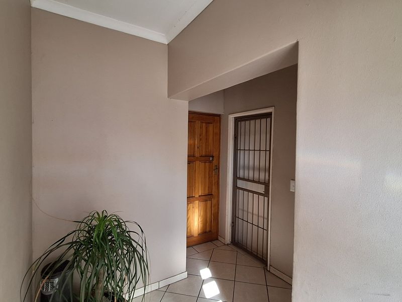 An entrance area featuring tiled flooring, a solid timber door, and a security gate, providing a functional and secure transition space.