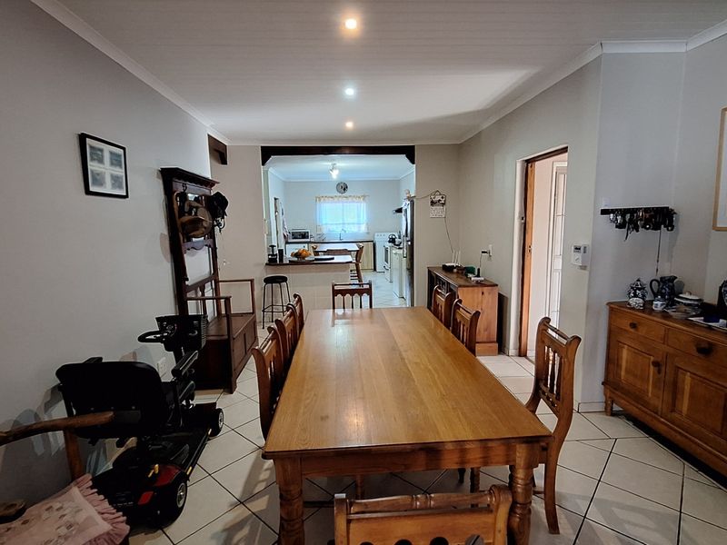 Open plan dining area flowing into a functional kitchen space with tiled flooring and recessed lighting throughout.