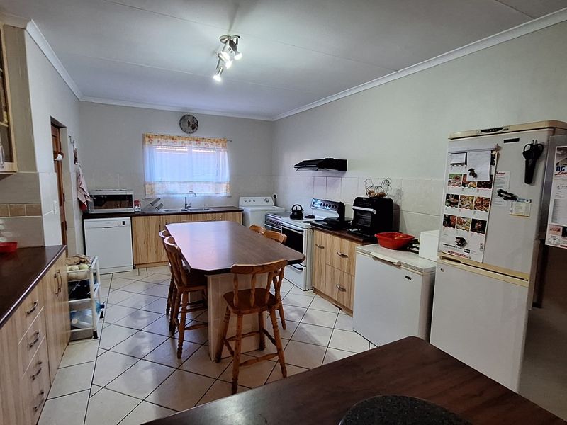 A functional kitchen featuring light wood cabinetry, laminate countertops, tiled flooring, and a central island with seating, providing a practical workspace.