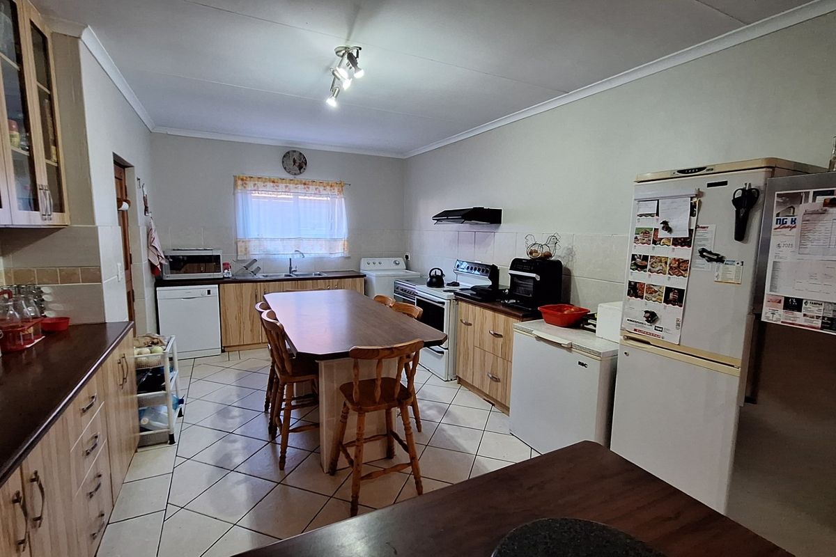A functional kitchen featuring light wood cabinetry, laminate countertops, tiled flooring, and a central island with seating, providing a practical workspace.