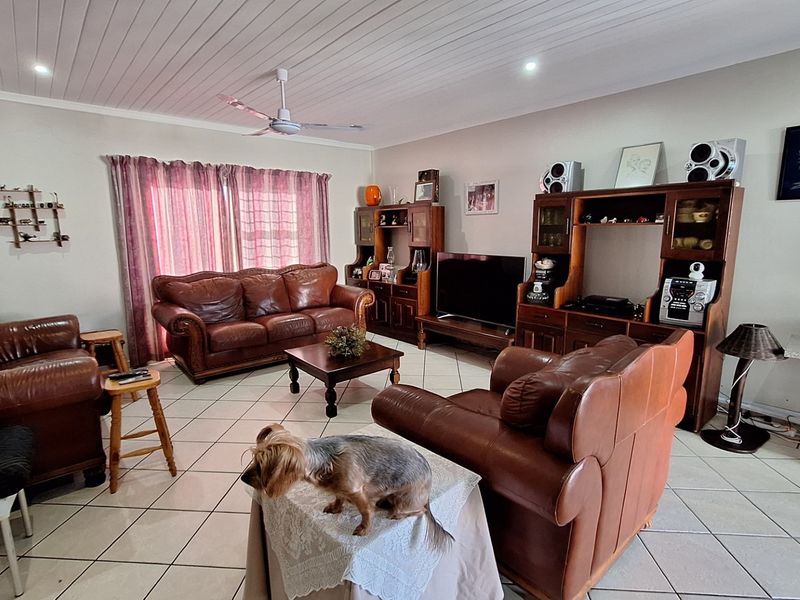 Spacious living room featuring tiled flooring, a tongue and groove ceiling with a central fan, and recessed lighting.