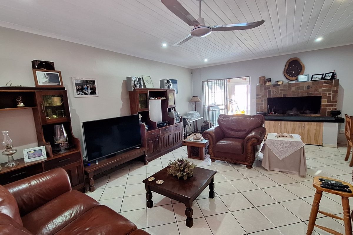 Spacious living room featuring tiled flooring, a built-in fireplace with stone cladding, and a ceiling fan, offering a comfortable and functional layout.