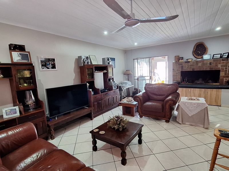 Spacious living room featuring tiled flooring, a built-in fireplace with stone cladding, and a ceiling fan, offering a comfortable and functional layout.