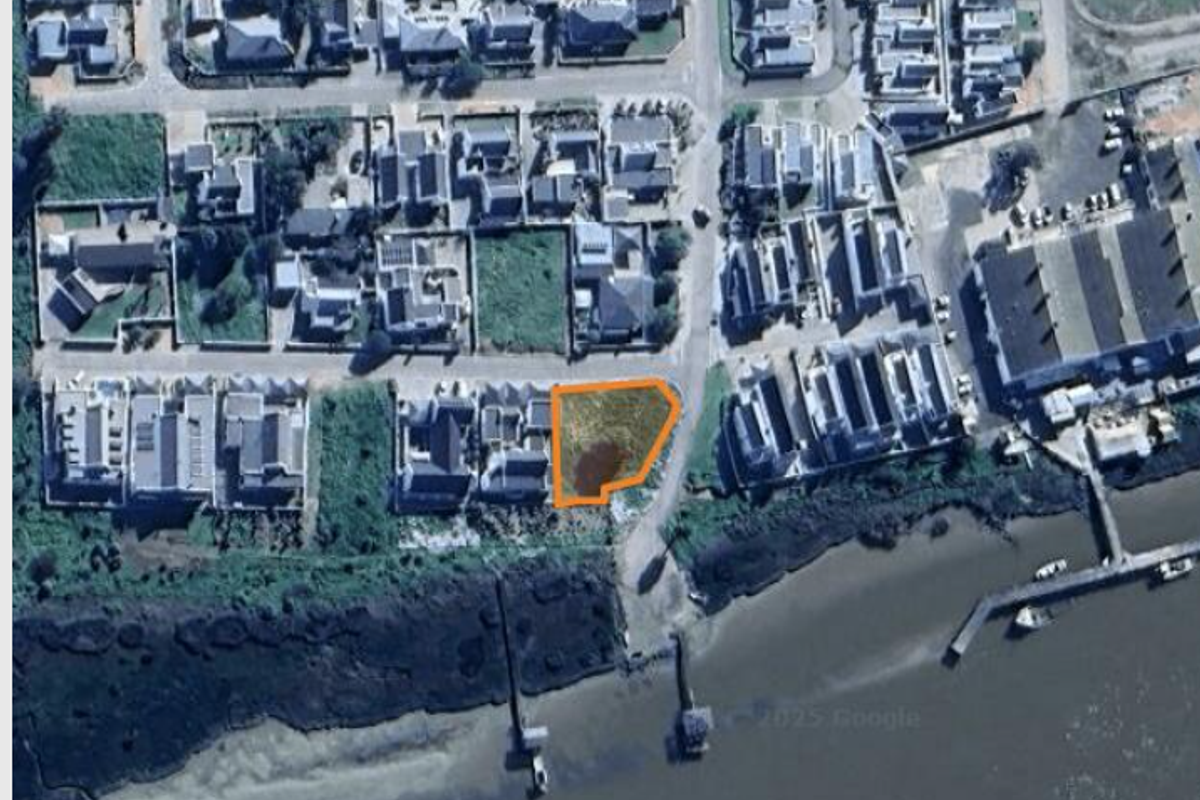 Aerial view of a vacant residential plot situated in a coastal neighborhood, highlighting its location and surrounding infrastructure.