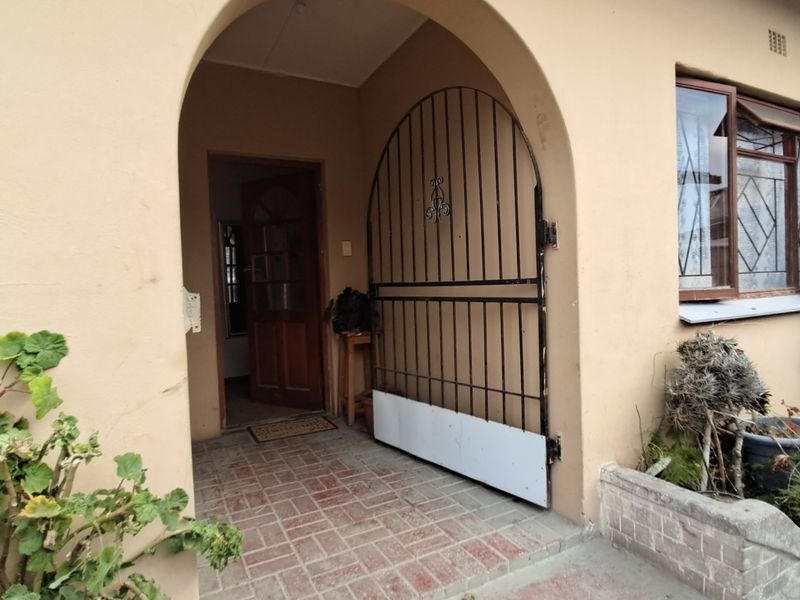 Covered arched entryway featuring brick paving, a wrought iron security gate, and a timber front door, providing a secure and classic entrance to the home.