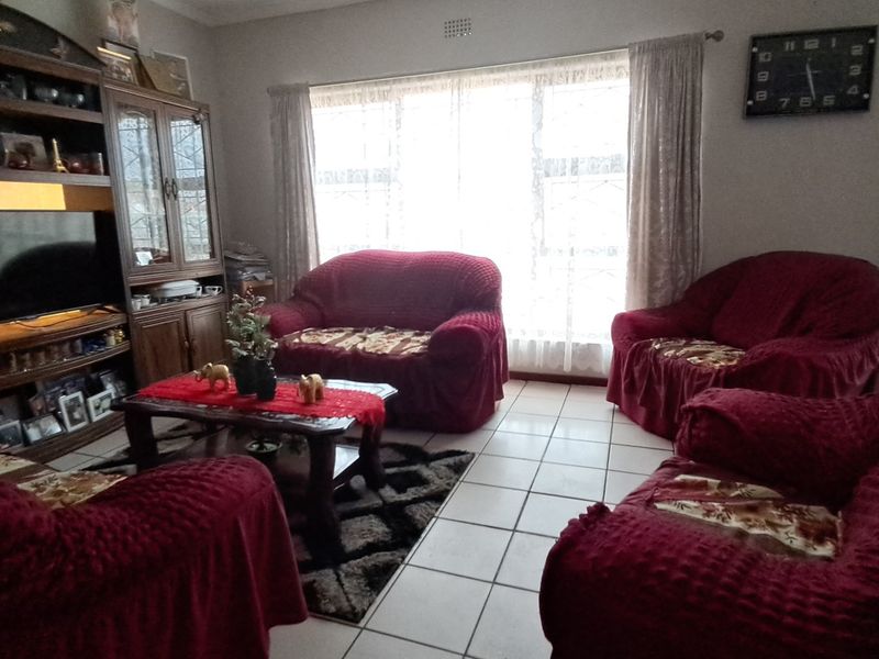 A living room featuring tiled flooring, a large window providing natural light, and a built-in display cabinet.