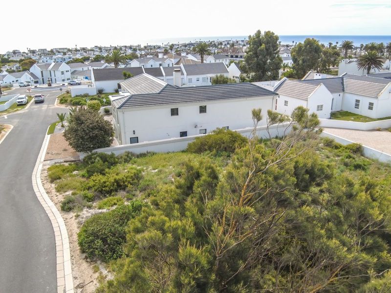 An aerial view of a vacant residential plot situated in a coastal estate, featuring established surrounding infrastructure and nearby residential properties.