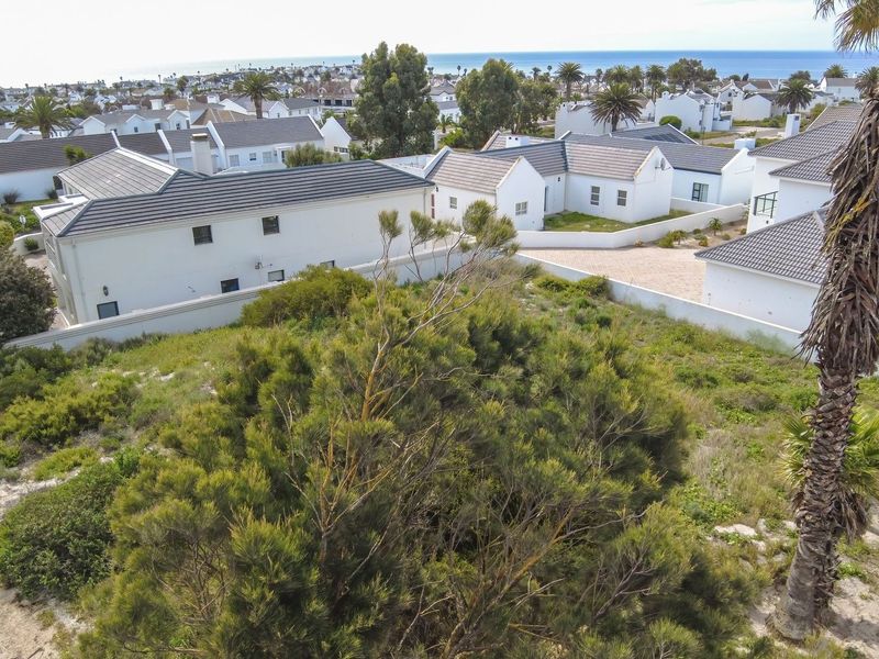 Aerial view of a vacant residential plot situated within a developed coastal estate, featuring established boundary walls and surrounding residential properties.