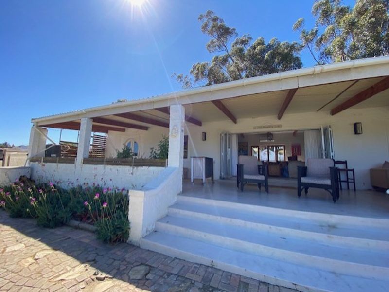 A spacious covered patio featuring exposed timber beams, concrete steps, and bi-fold doors providing seamless access to the interior living space.