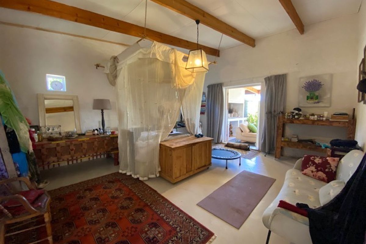 Spacious bedroom featuring exposed timber ceiling beams, neutral flooring, and direct access to an outdoor patio area through sliding glass doors.