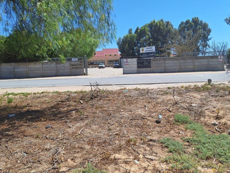 Street view of the vacant residential land showing the perimeter precast concrete wall, security fencing, and gated entrance.