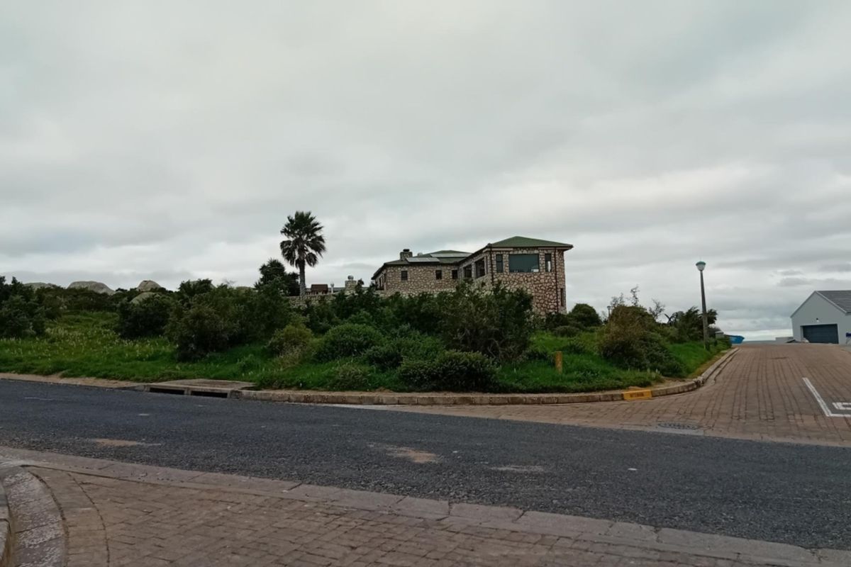 A street-level view of a residential property featuring a stone-clad building situated on a corner lot with paved access roads.