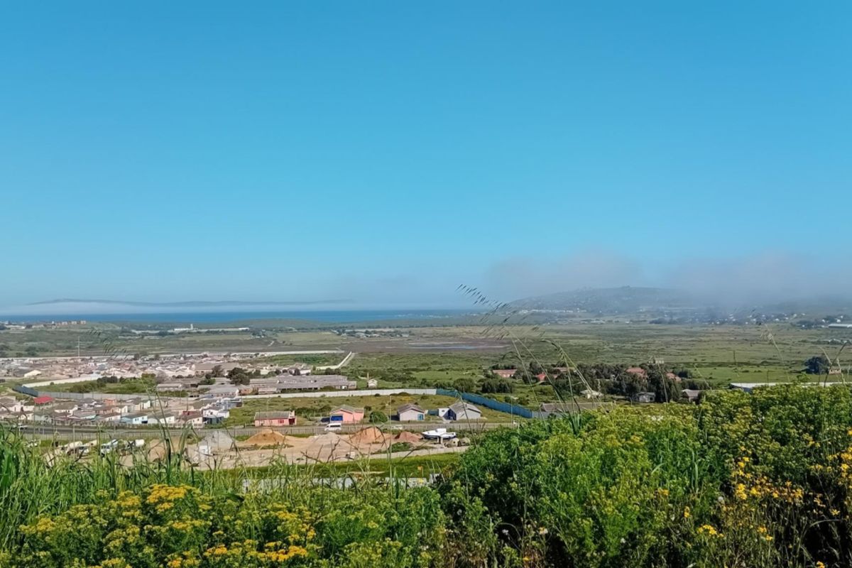 A wide-angle elevated view overlooking the surrounding landscape, residential area, and distant coastline under a clear blue sky.