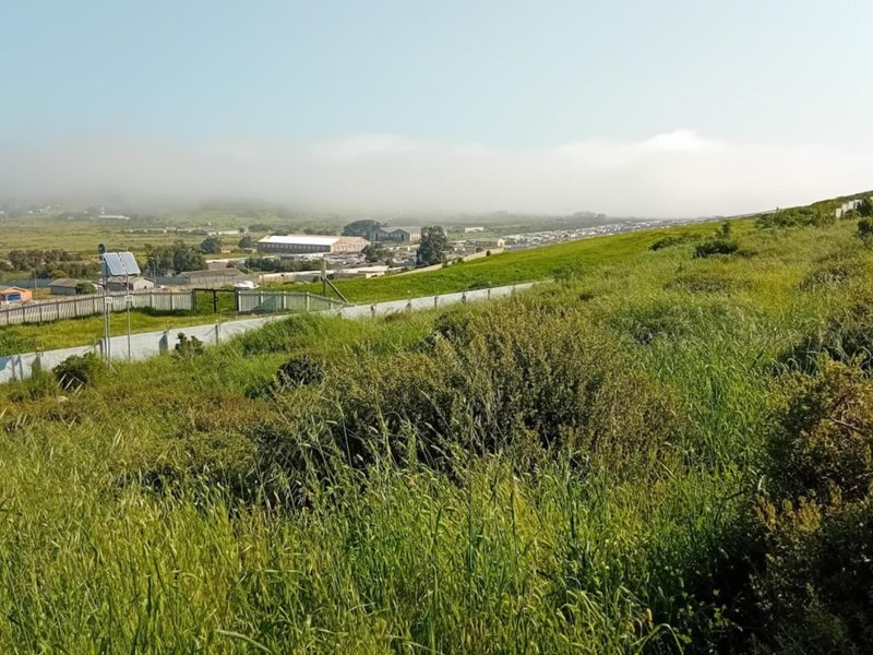 A view of the vacant residential land featuring natural sloped terrain and perimeter fencing, overlooking the surrounding neighborhood and landscape.