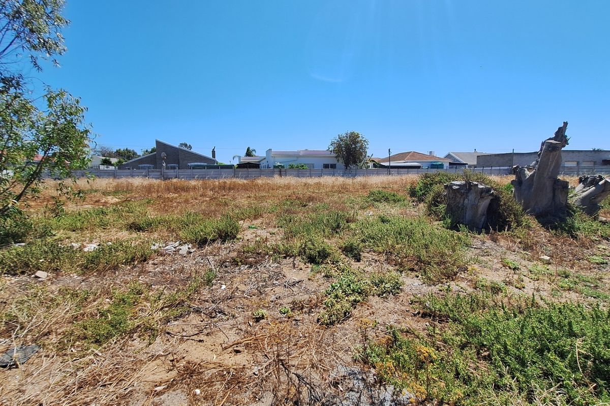 A vacant residential plot featuring a precast concrete boundary wall and natural ground cover, ready for development.