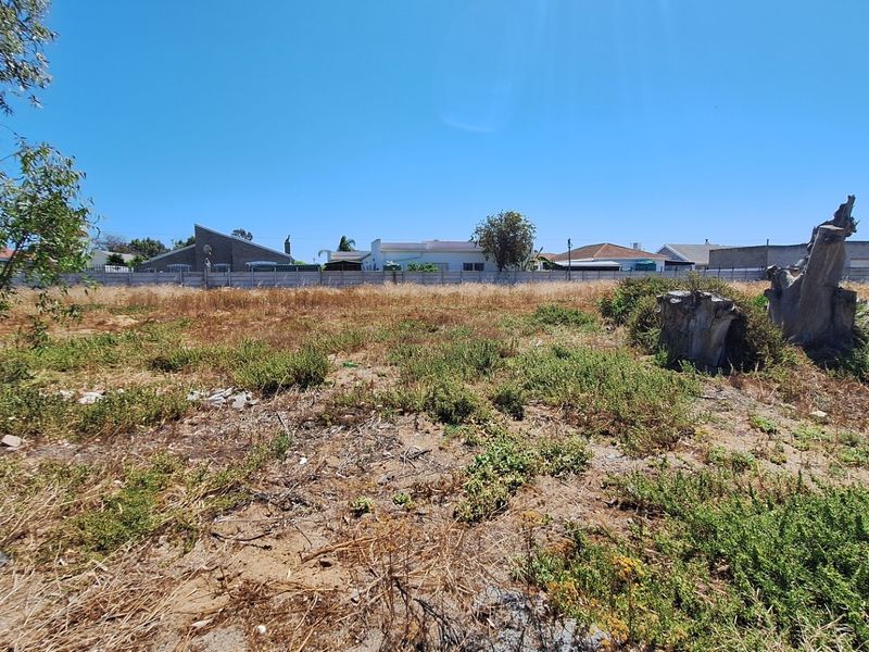 A vacant residential plot featuring a precast concrete boundary wall and natural ground cover, ready for development.