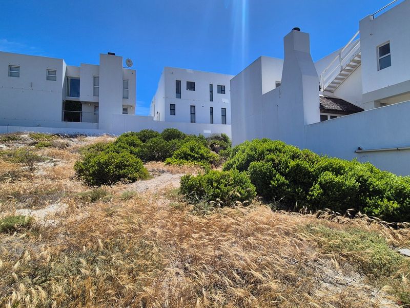View of the rear elevation of the residential property, featuring white rendered walls, an external staircase, and a chimney stack set against a landscaped garden.