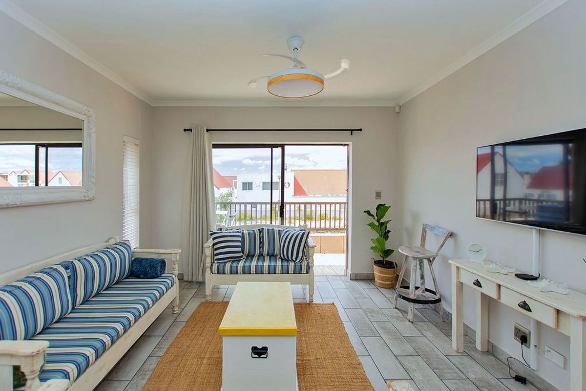 A bright living room featuring tiled flooring, a ceiling fan, and a sliding glass door providing access to an outdoor balcony area.