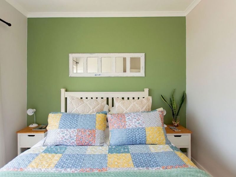 A well-maintained bedroom featuring a green accent wall, neutral side walls, and classic coving detail.