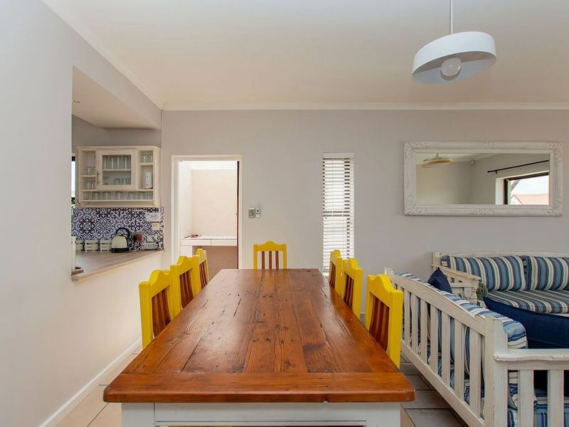 Open plan living and dining area featuring tiled floors, a kitchen pass-through with decorative backsplash, and neutral wall finishes.