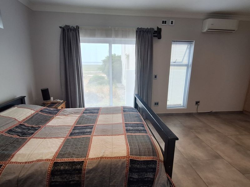 Spacious bedroom featuring tiled flooring, built-in cupboards, an air conditioning unit, and a sliding glass door providing natural light and outdoor access.