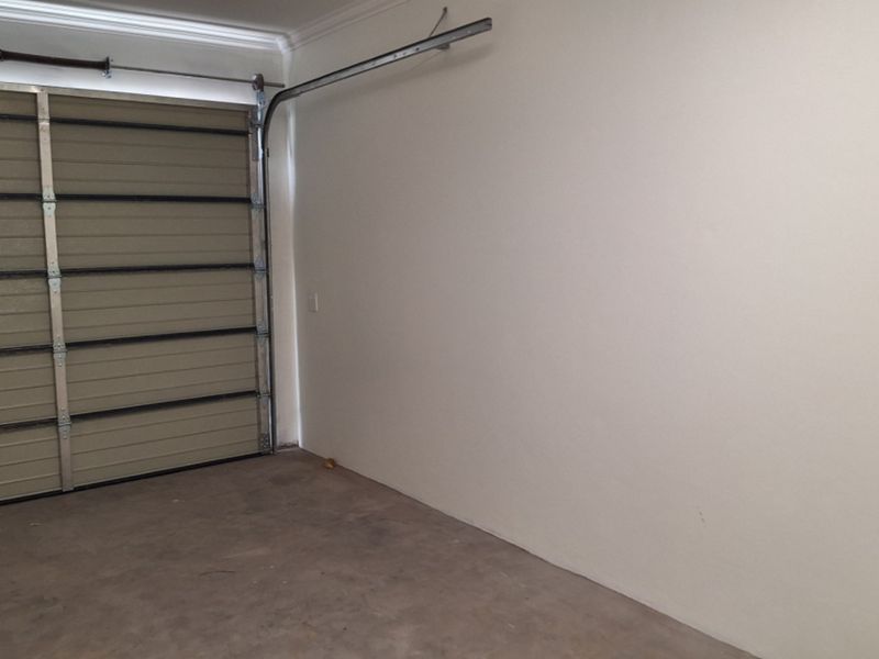A clean, empty garage space featuring a sectional garage door and concrete flooring, providing secure parking or additional storage potential.