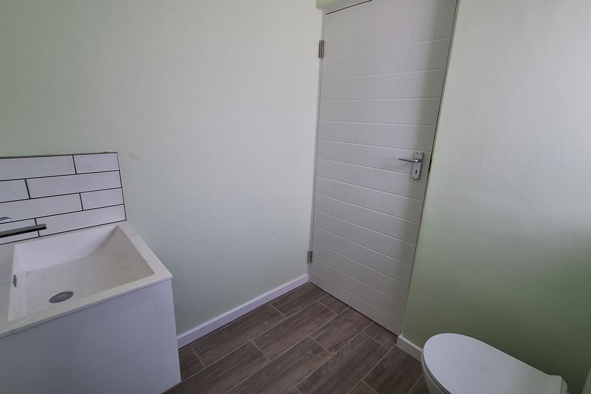 A clean, modern bathroom featuring a vanity basin with subway tile splashback, tiled flooring, and a white internal door.