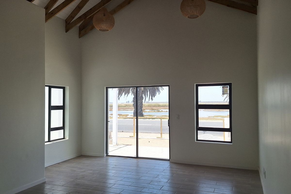 Spacious living area featuring a high vaulted ceiling with exposed timber rafters, tiled flooring, and large windows providing natural light and scenic views.